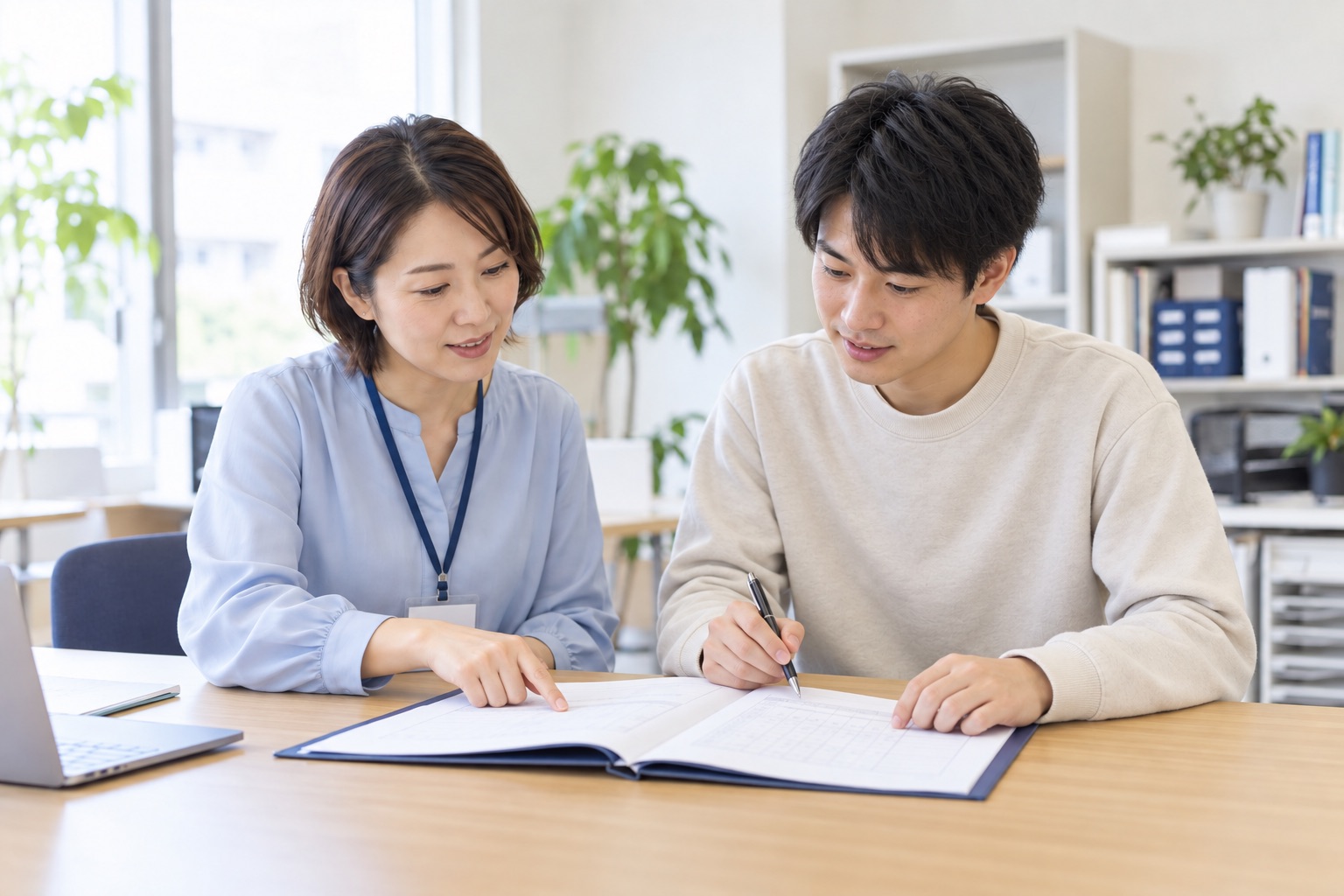 支援員が若い利用者の相談に乗り、書類を一緒に確認するイメージ写真